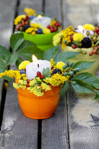 Candle holder decorated with autumn flowers and other plants
