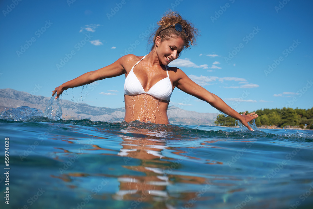 Naklejka premium Beautiful young woman in the sea splashing water
