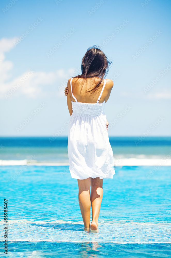 woman in luxury resort near swimming pool - back view woman in luxury resort near swimming pool - back view