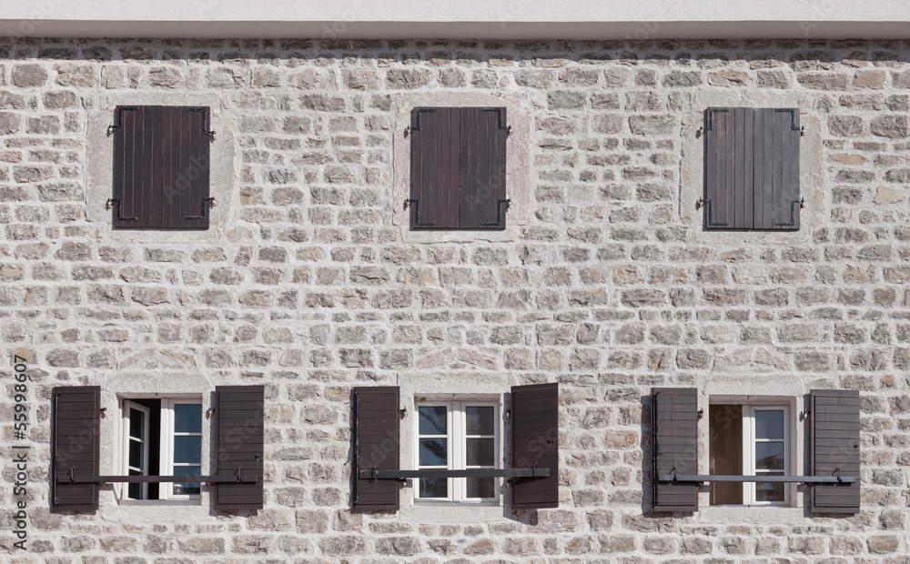 Old stone facade with  windows and jalousies