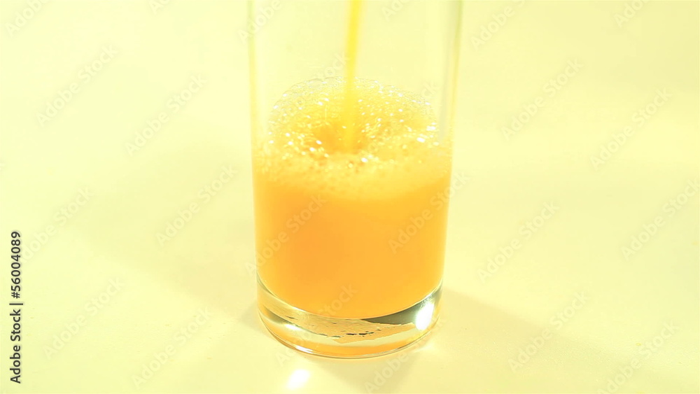 Bright orange juice flowing in a glass close up Bright orange juice flowing in a glass close up