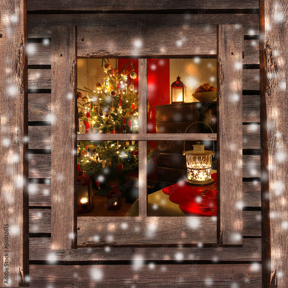 Christmas tree and fireplace seen through a wooden cabin window