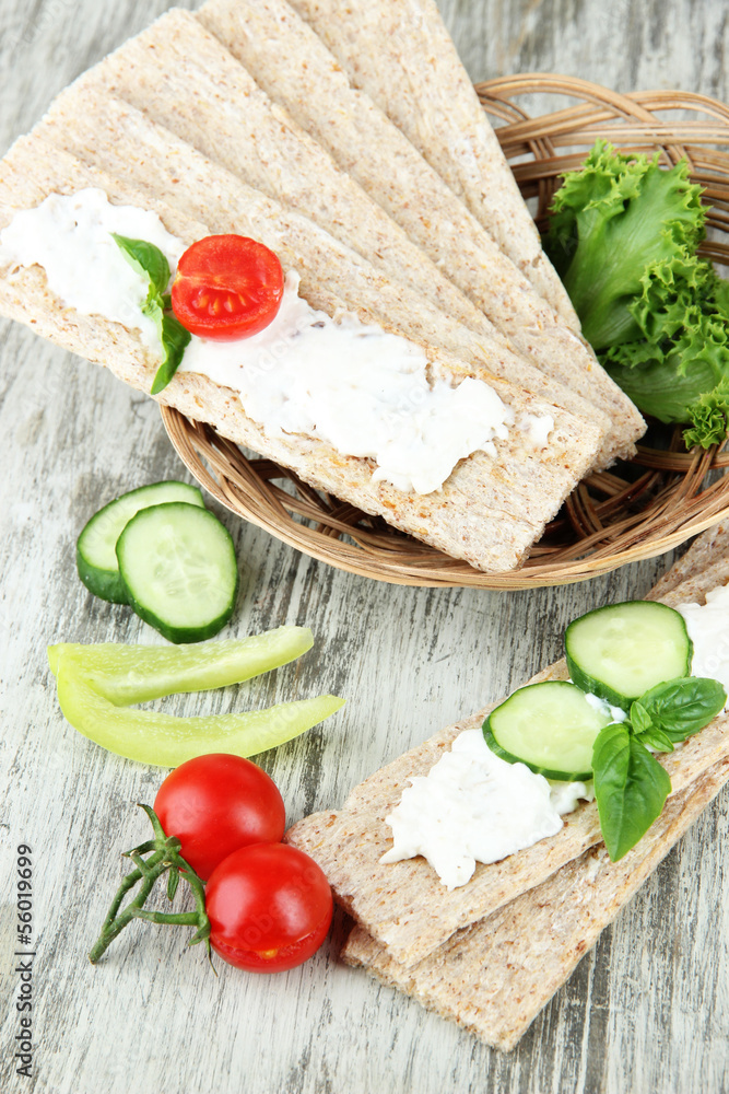 Tasty crispbreads with vegetables on wooden background Tasty crispbreads with vegetables on wooden background