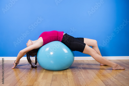 Fitness woman exercising with ball indoors.