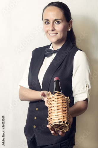 Beautiful waitress offering a bottle of wine