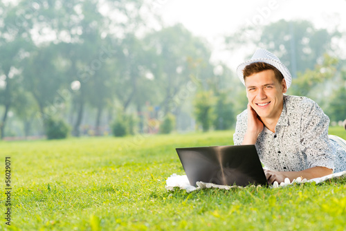 young man working in the park with a laptop