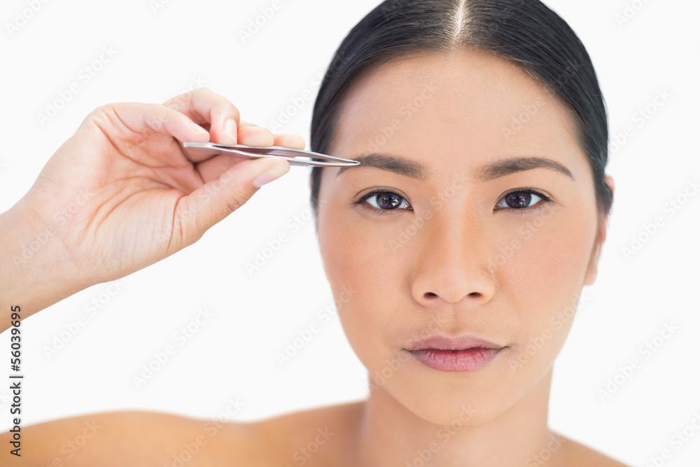 Concentrated natural model using tweezers for her eyebrow