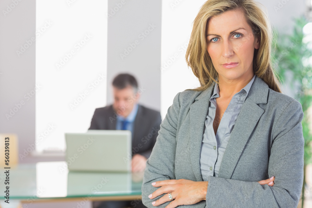 Unsmiling businesswoman looking at camera crossed arms with a bu Unsmiling businesswoman looking at camera crossed arms with a bu