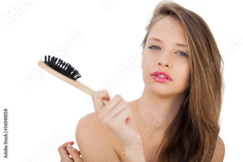 Pensive brunette model holding a hairbrush