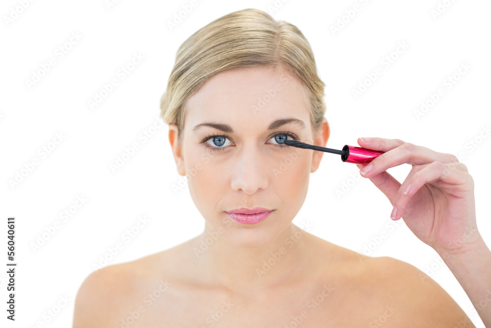 Concentrated young blonde woman applying mascara