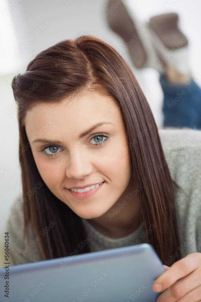 Smiling girl looking at camera using a tablet pc on a sofa Smiling girl looking at camera using a tablet pc on a sofa