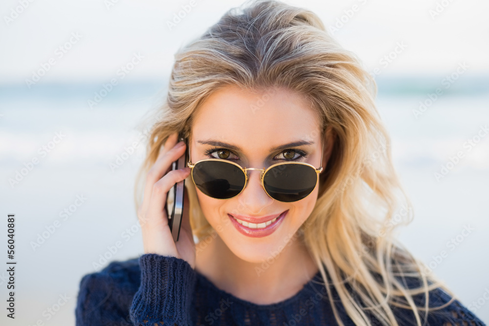 Cheerful gorgeous blonde on the phone looking over her sunglasse