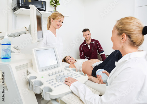 Gynecologists And Expectant Couple In Clinic