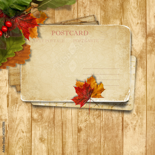 Autumn leaves over wooden background with postcard