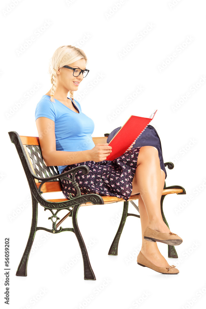 Smiling blond female student sitting on a bench reading a book Smiling blond female student sitting on a bench reading a book