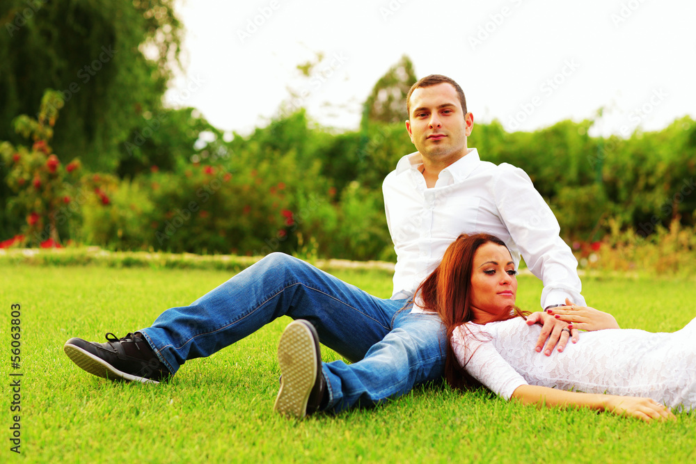 Fototapeta premium Young couple resting an the lawn in park