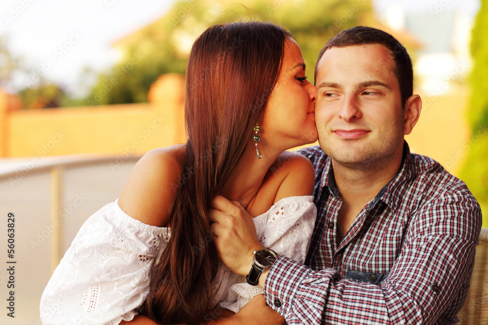 Naklejka premium Beautiful girl kissing her boyfriend on the cheek