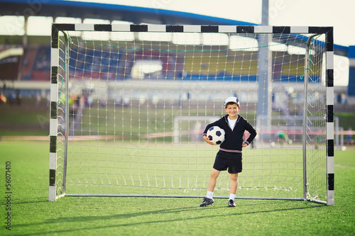 Little boy plays football on stadium