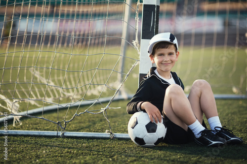 Little boy plays football on stadium