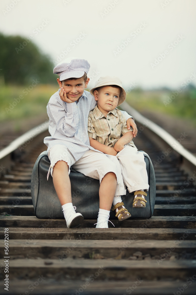 Two happy boys with suitcase on railways Two happy boys with suitcase on railways