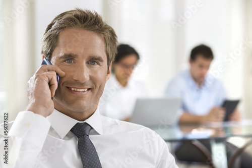 Business man speaking on the cell phone while in a meeting