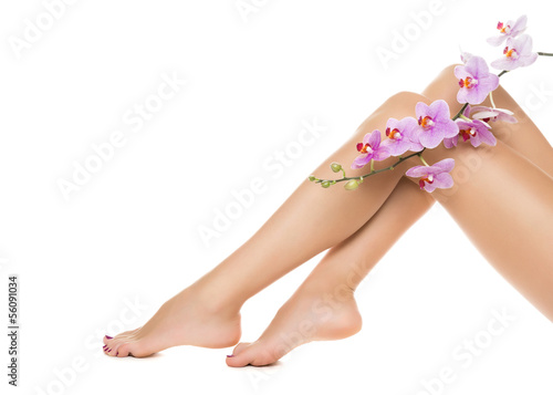 Long woman legs and orchids isolated on white background.