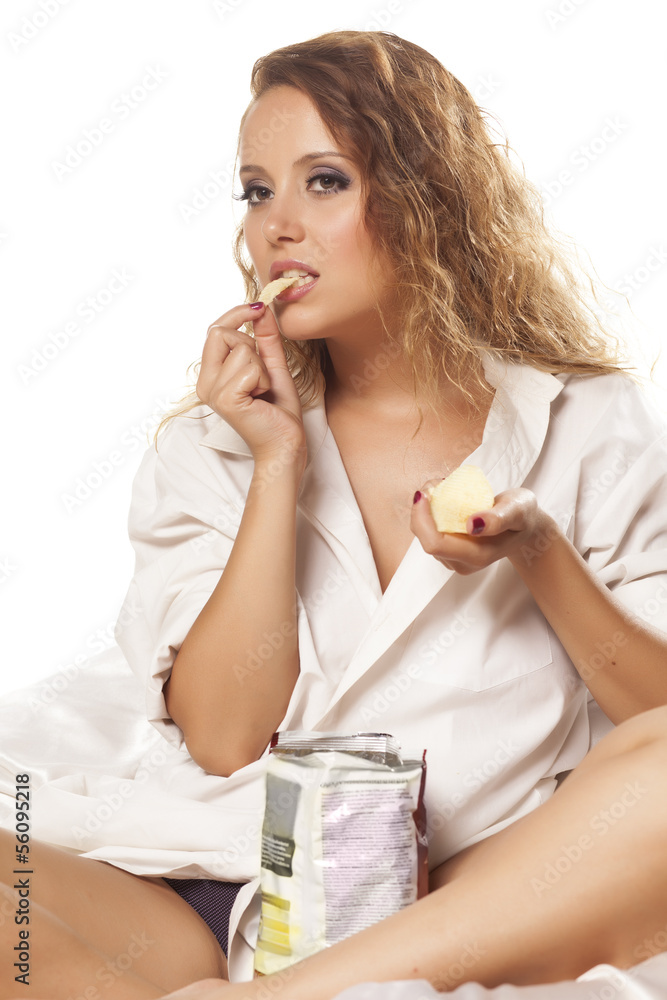 happy girl in a white shirt voraciously eating potato chips happy girl in a white shirt voraciously eating potato chips