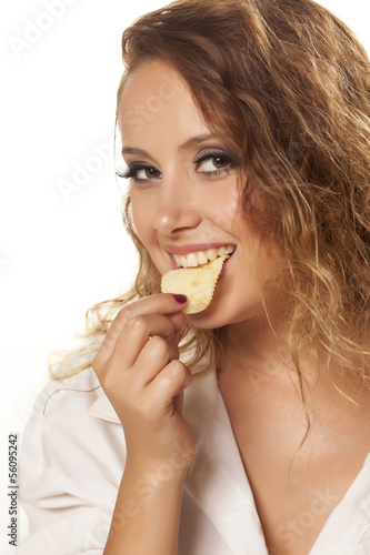 beautiful girl in a white shirt eats potato chips