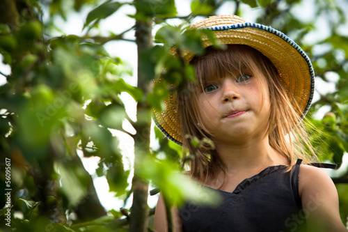 Little lovely girl posing in a straw hat in the park
