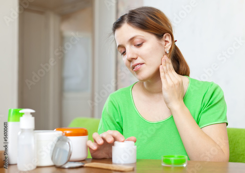  woman  in green caring for face with cream