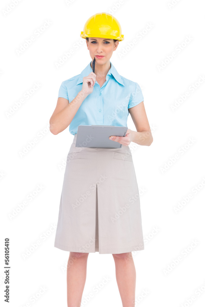 Thoughtful attractive architect holding clipboard Thoughtful attractive architect holding clipboard