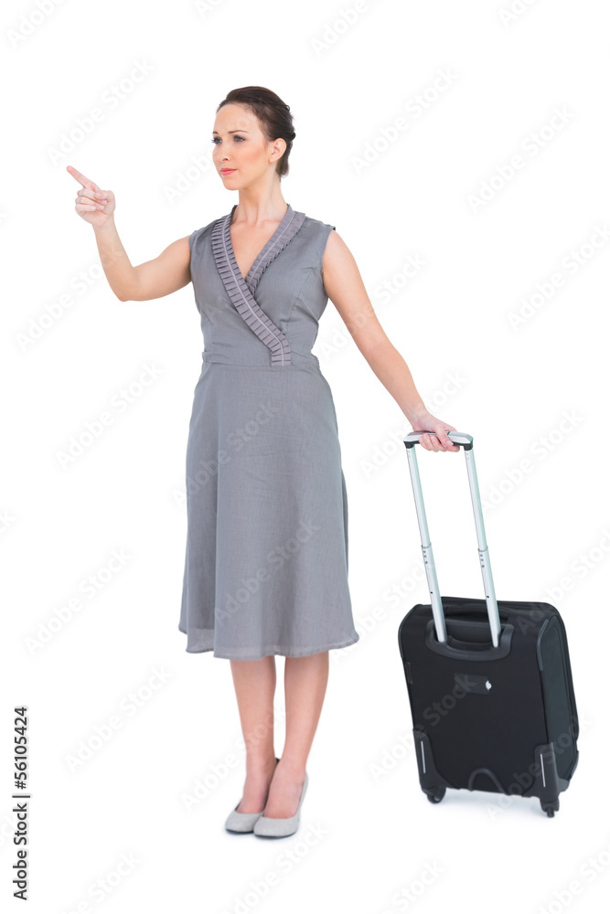 Smiling gorgeous woman carrying her suitcase pointing finger Smiling gorgeous woman carrying her suitcase pointing finger