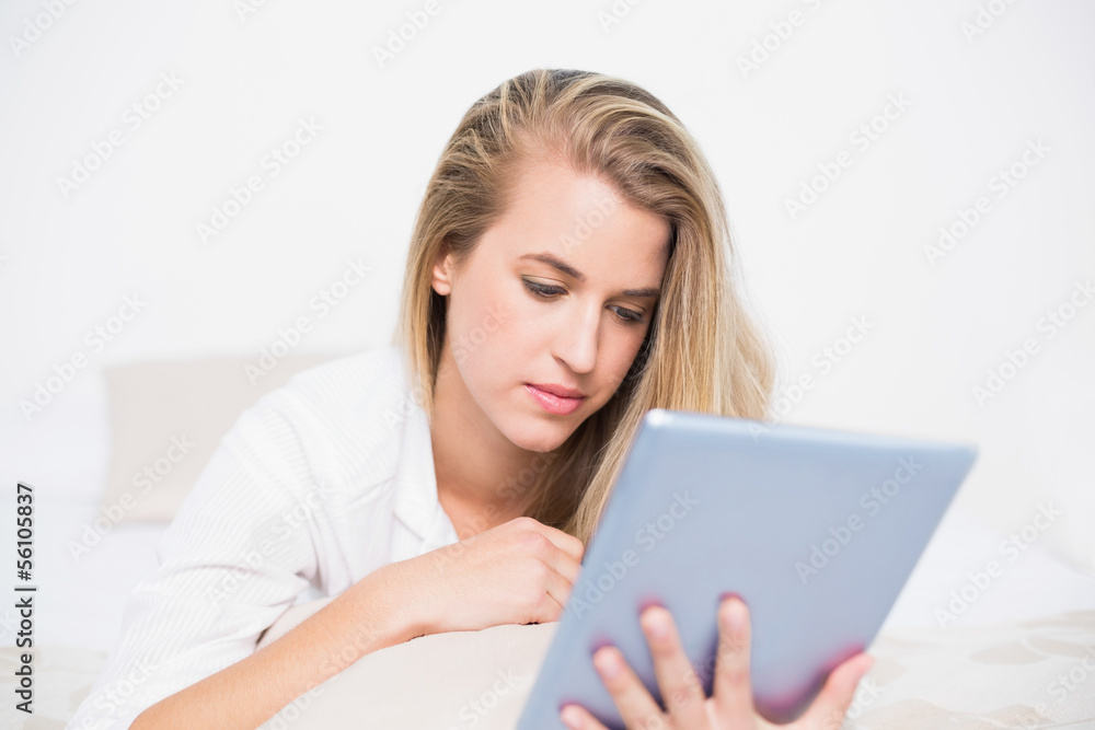Focused pretty model using her tablet pc lying on cosy bed Focused pretty model using her tablet pc lying on cosy bed