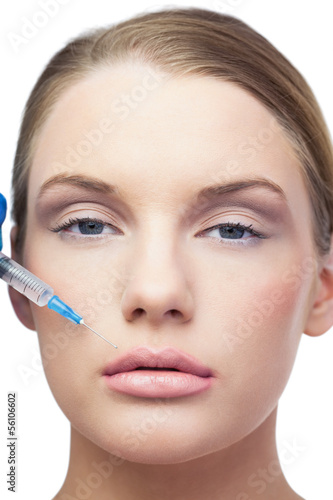Close-up young woman receives cosmetic injection above lips