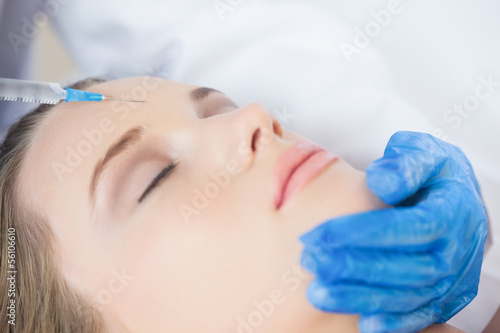 Surgeon making injection on forehead on content woman lying