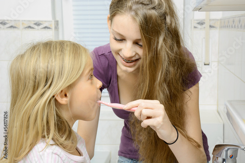 Teenager putzt kleinem Mädchen die Zähne