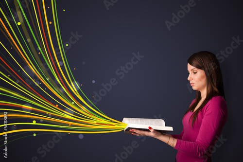 Pretty young woman reading a book while colorful lines are comin photo