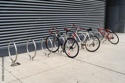 3 bikes are locked to modern looking sidewalk racks in Toronto