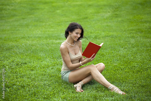 Young beautiful young woman reading a book outdoor