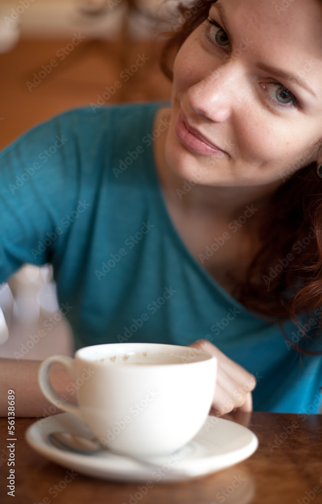 Redhead women sitting in the cafee with cup of coffee on the tab Redhead women sitting in the cafee with cup of coffee on the tab
