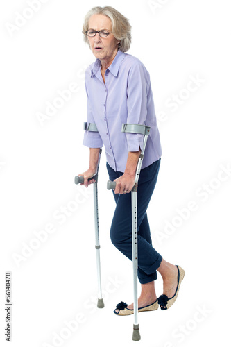 Aged woman in pain walking with crutches © stockyimages
