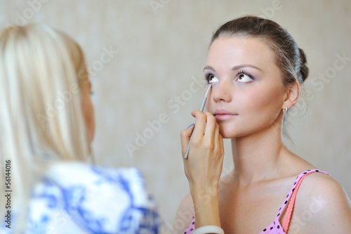 Beautiful woman applying wedding make-up by make-up artist