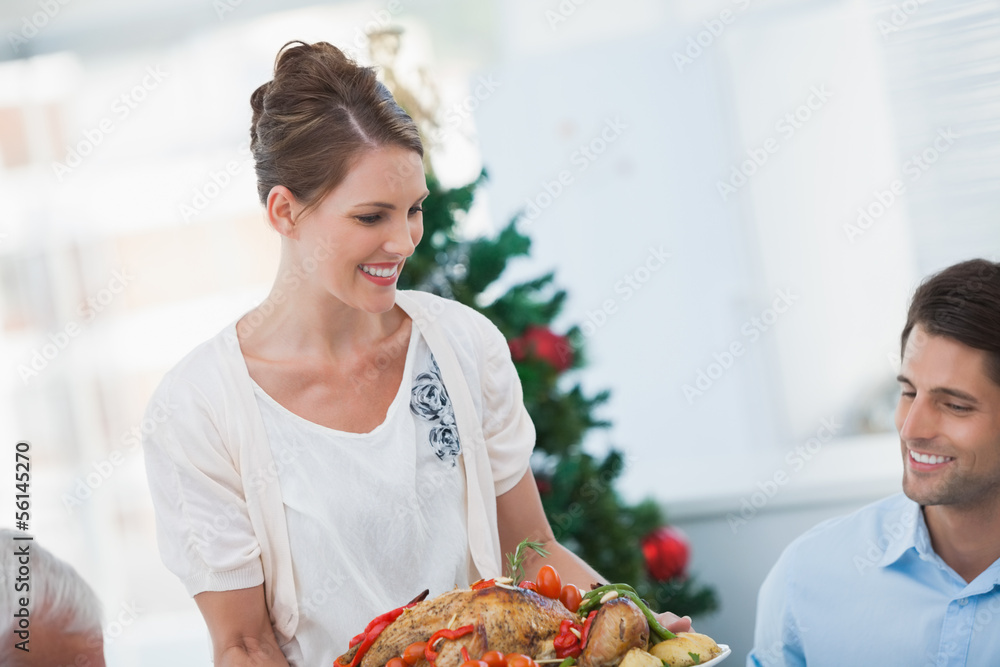 Attractive woman bringing a roast chicken at table Attractive woman bringing a roast chicken at table