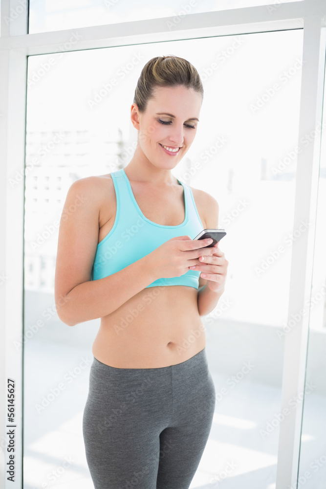 Fit smiling woman using phone