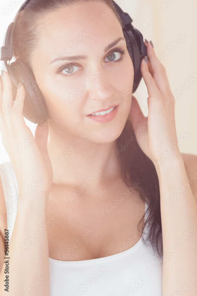 Beautiful brunette sitting on bed listening to music