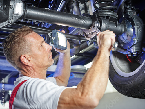 Mechanic in a garage checks a tyre of a car photo