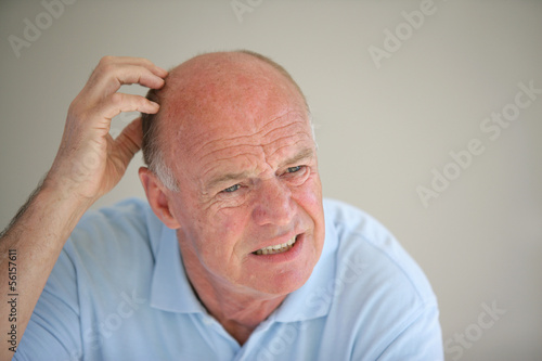 Senior bald man scratching his head