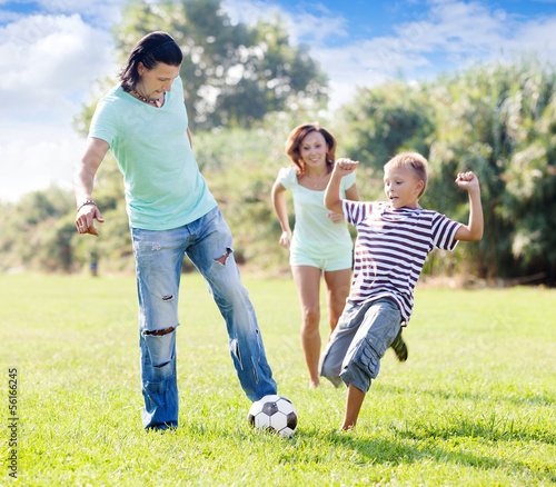 family with teenager child playing with soccer ball