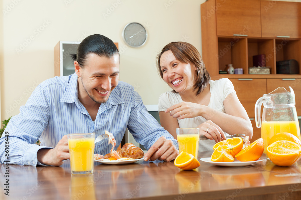 Happy  couple having breakfast with juice in morning at home