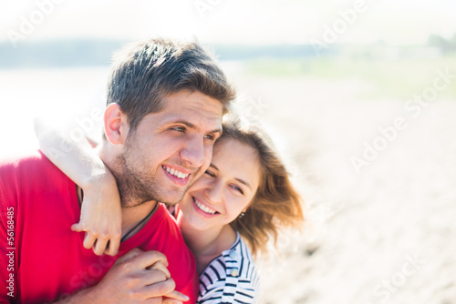 Young man having his woman piggyback a blue sky on a beach